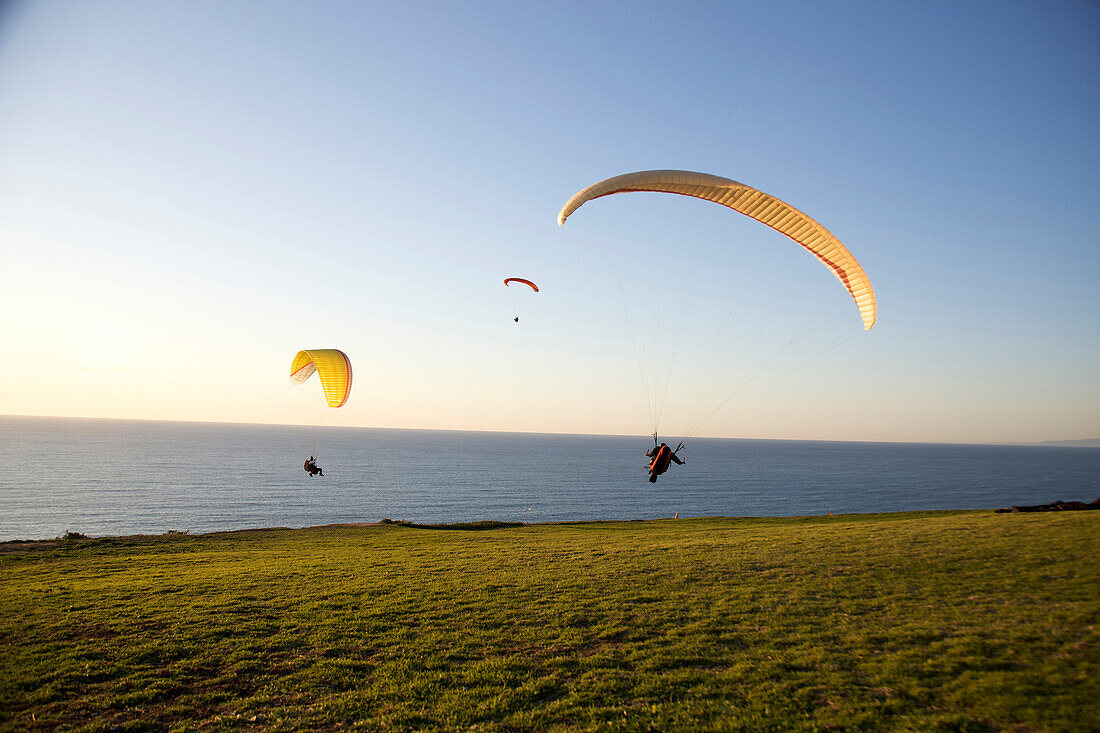 Paraglider takes off as two other paragliders ride by from the paragliding port in Torrey Pines, San Diego, California San Diego, California, USA