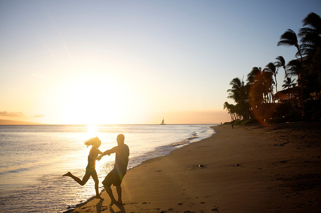 Happy, young couple dance and play at the beach right before sunset in Maui, Hawaii Maui, Hawaii, USA