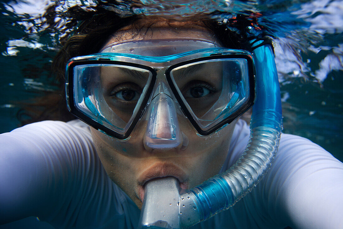 Young woman looks straight at the camera through a mask while snorkling in Maui, Hawaii Maui, Hawaii, USA