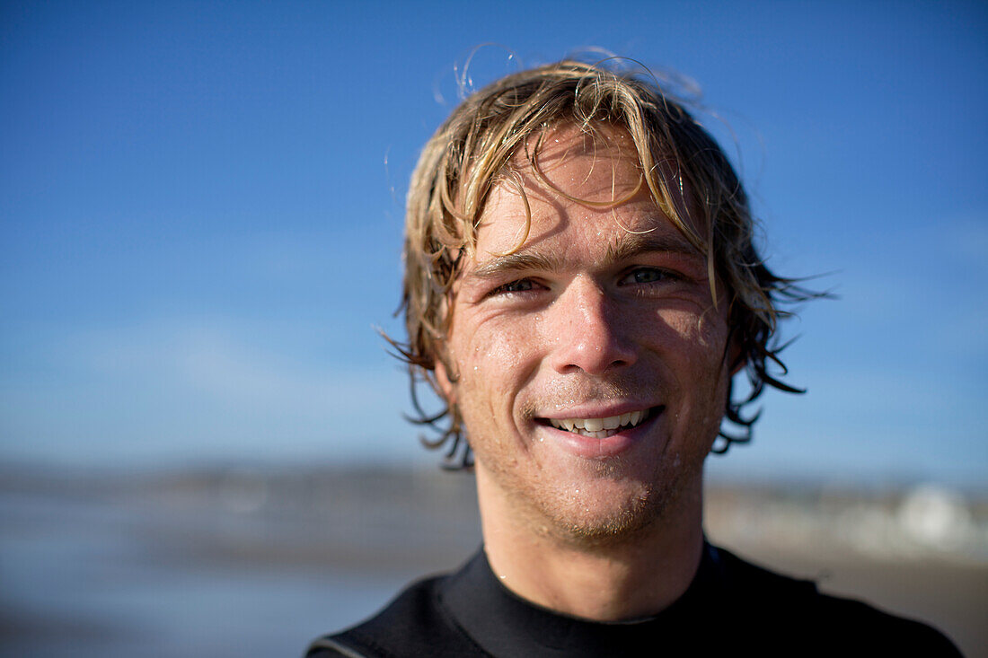 Young male surfer at Pacific Beach in San Diego, California on a sunny day smiles and look straight at the camera San Diego, California, USA