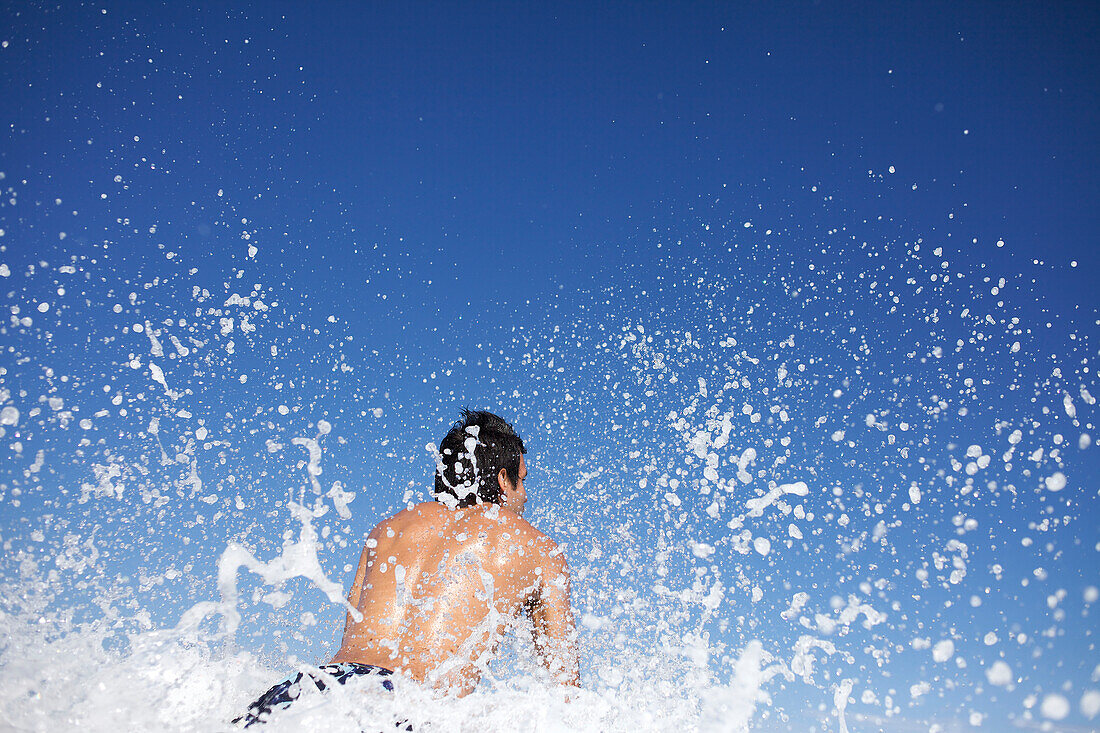 Male surfer splashing water at the beach in La Jolla Shore, San Diego, California San Diego, California, USA