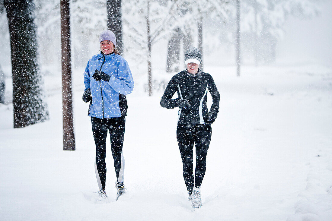 Two women run down Mountain Avenue in a snowstorm Fort Collins, Colorado, USA