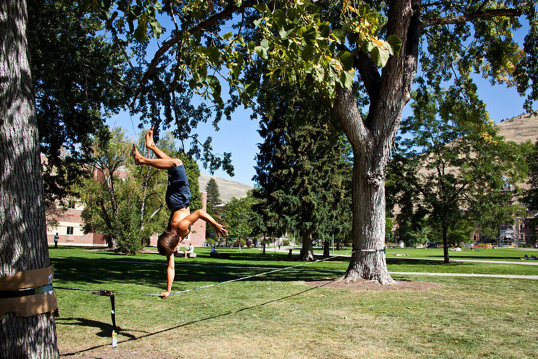 A professional slackliner plays around on the slackline on a university campus in Missoula, Montana Missoula, Montana, USA