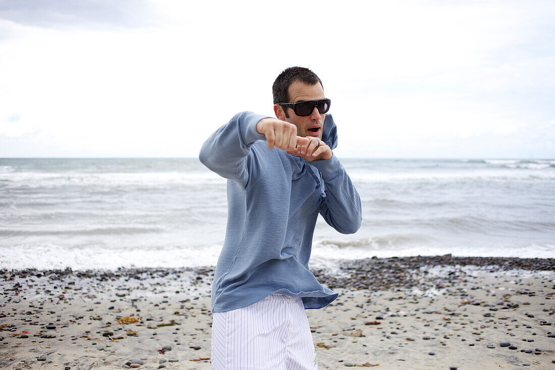 Male pretends he is fighting at the beach San Diego, California, USA