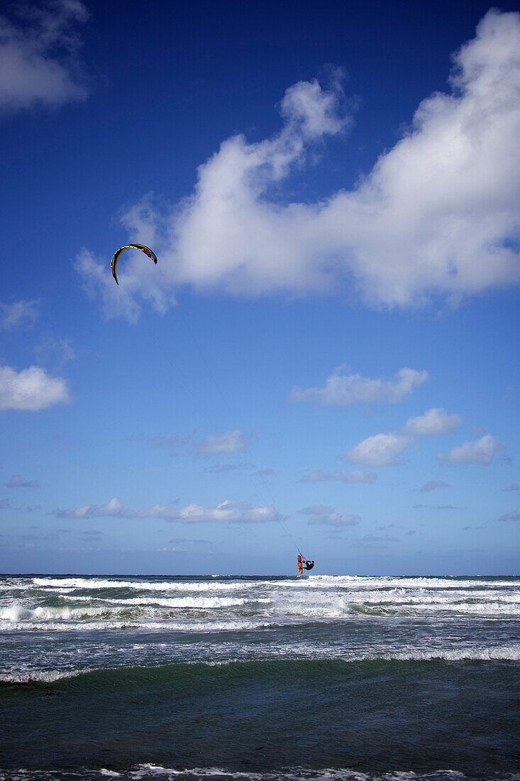 Kitesurfer jumps high on his kitesurf on a sunny day with a few clouds in the sky Cardiff-by-the-sea, California, USA