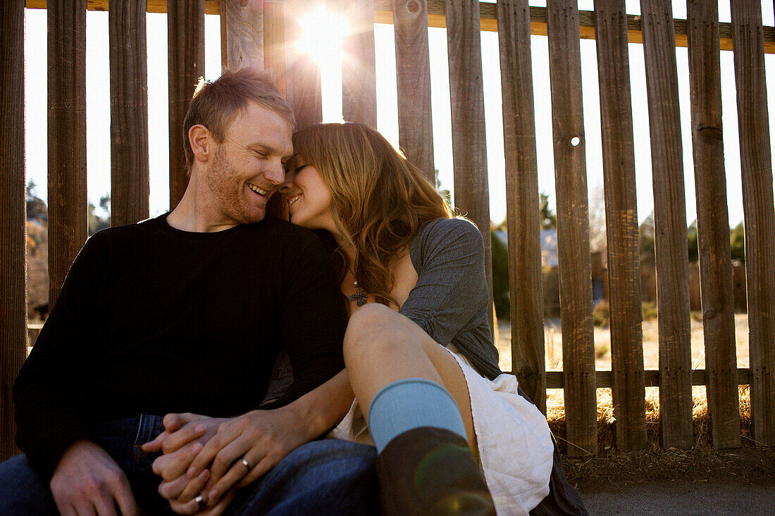 Couple sits against a fence San Diego, California, USA