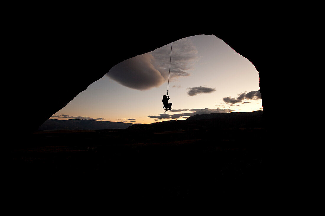 Young adult male rappels down an arch in Colorado Rifle, Colorado, USA