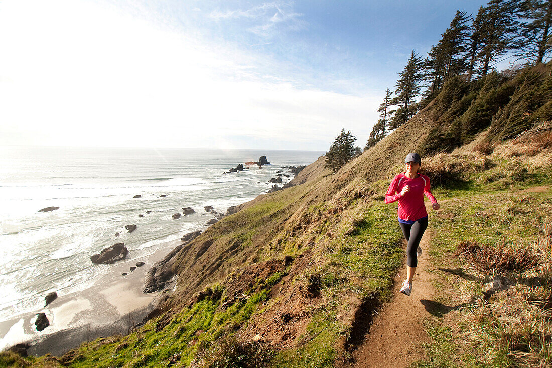 Woman trail running along the Oregon coast Cannon Beach, Oregon, USA
