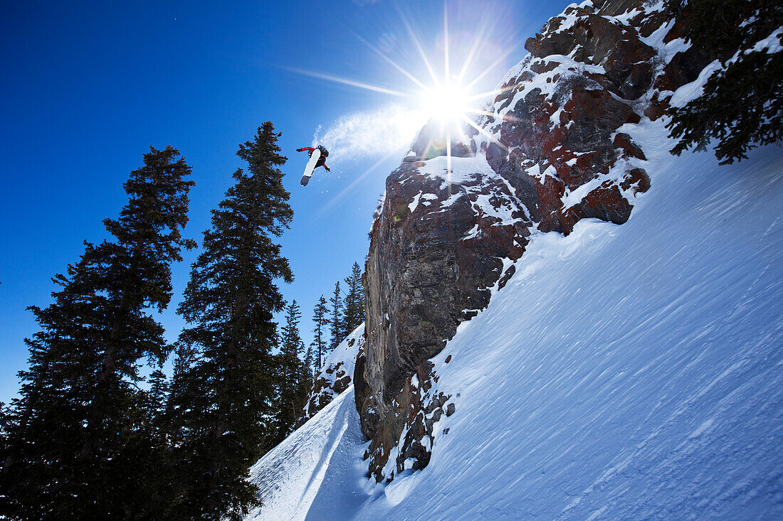 Male snowboarder spins off a 60 foot cliff in Utah Salt Lake City, Utah, USA