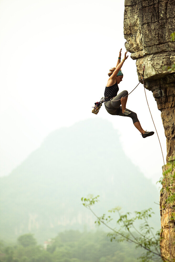 Caucasian female climber falling on a lead climb in China Yangshuo County, Guilin, Guangxi, China