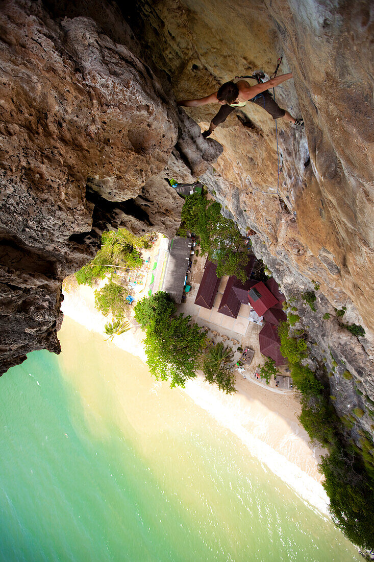 Female Austrian climber spans the wall  on a high limestone cliff in Thailand Tonsai Beach, Krabi, Thailand
