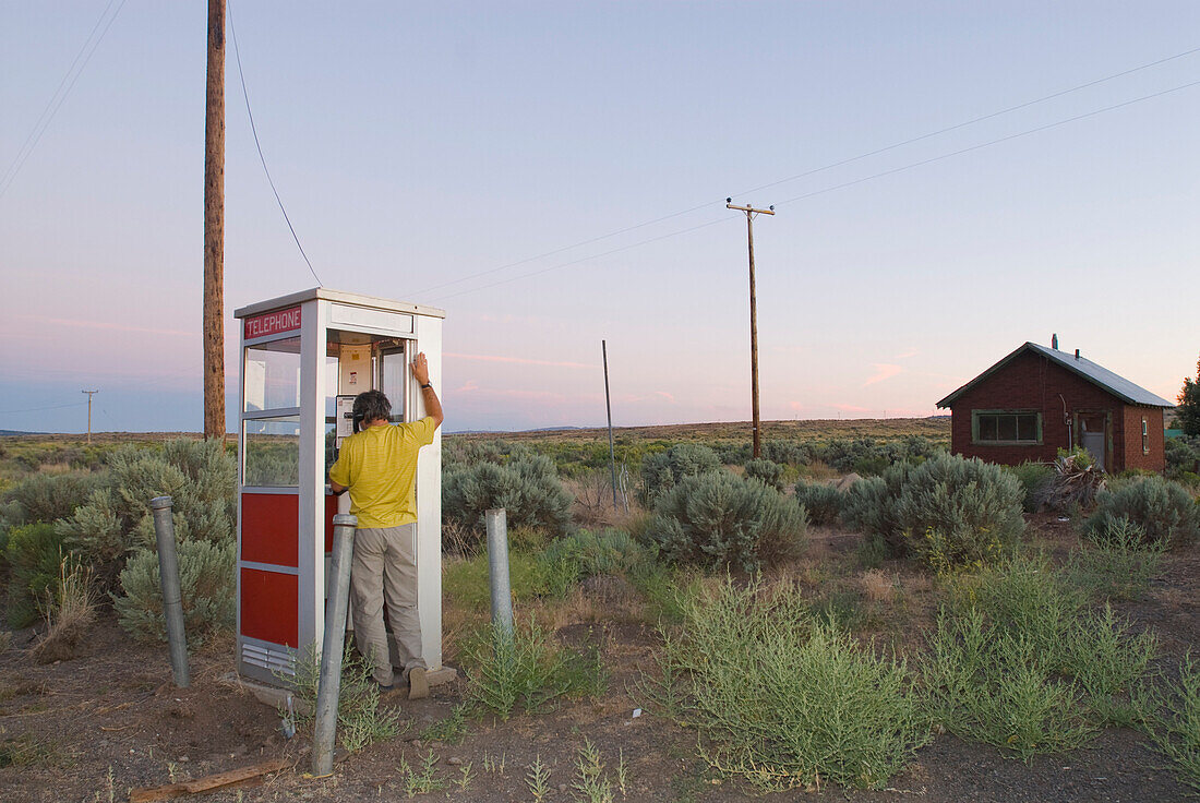 A man phones from a isolated phone booth OR, USA