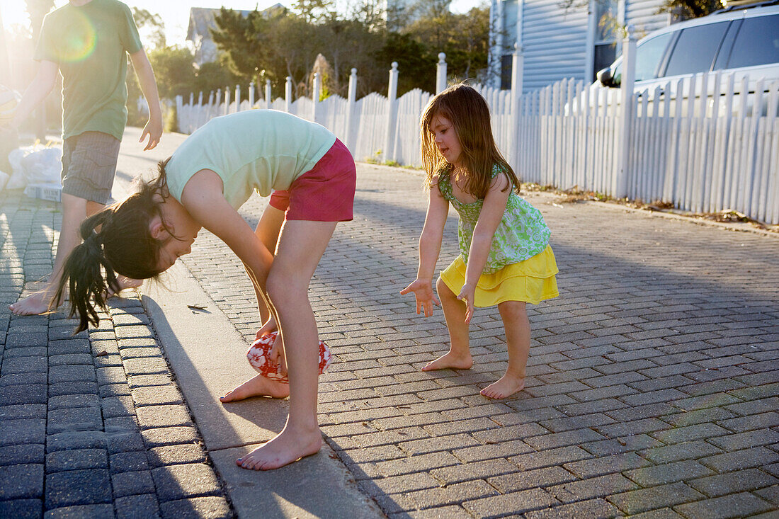 Two little girls are playing football in an alleyway with the sun in background Destin, Florida, USA