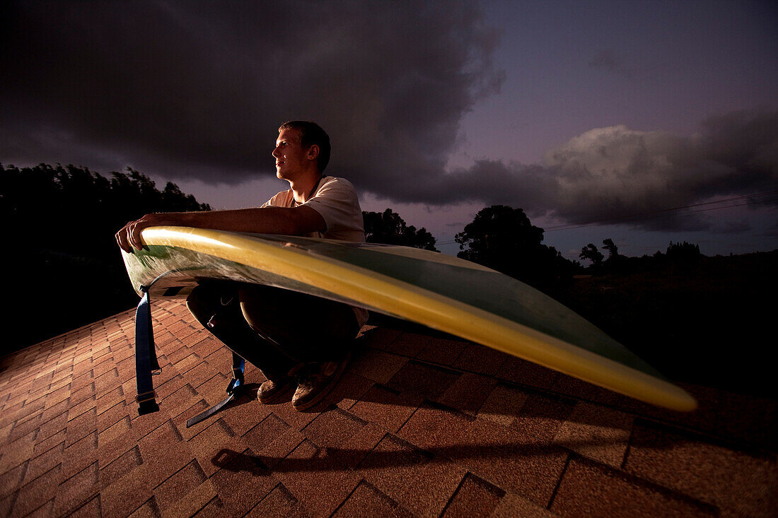 Portrait of a man on a roof with a waveski at sunset Ha'iku, Hawaii, USA