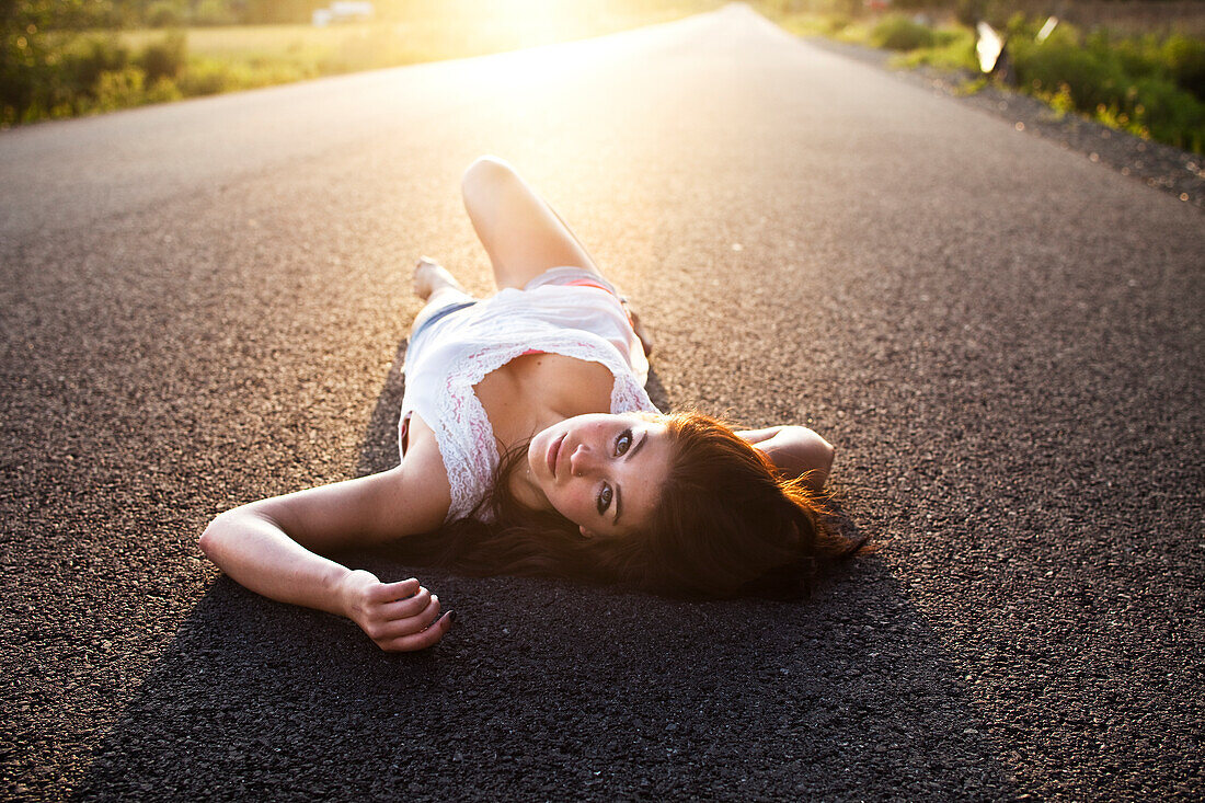A girl lies on the road at sunset in Idaho Sandpoint, Idaho, USA