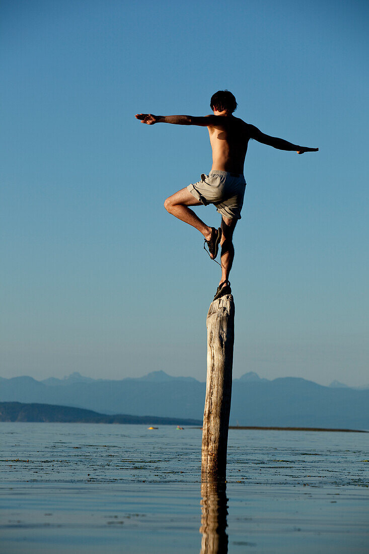 Man balances on log in British Columbia Tofino, British Columbia, Canada
