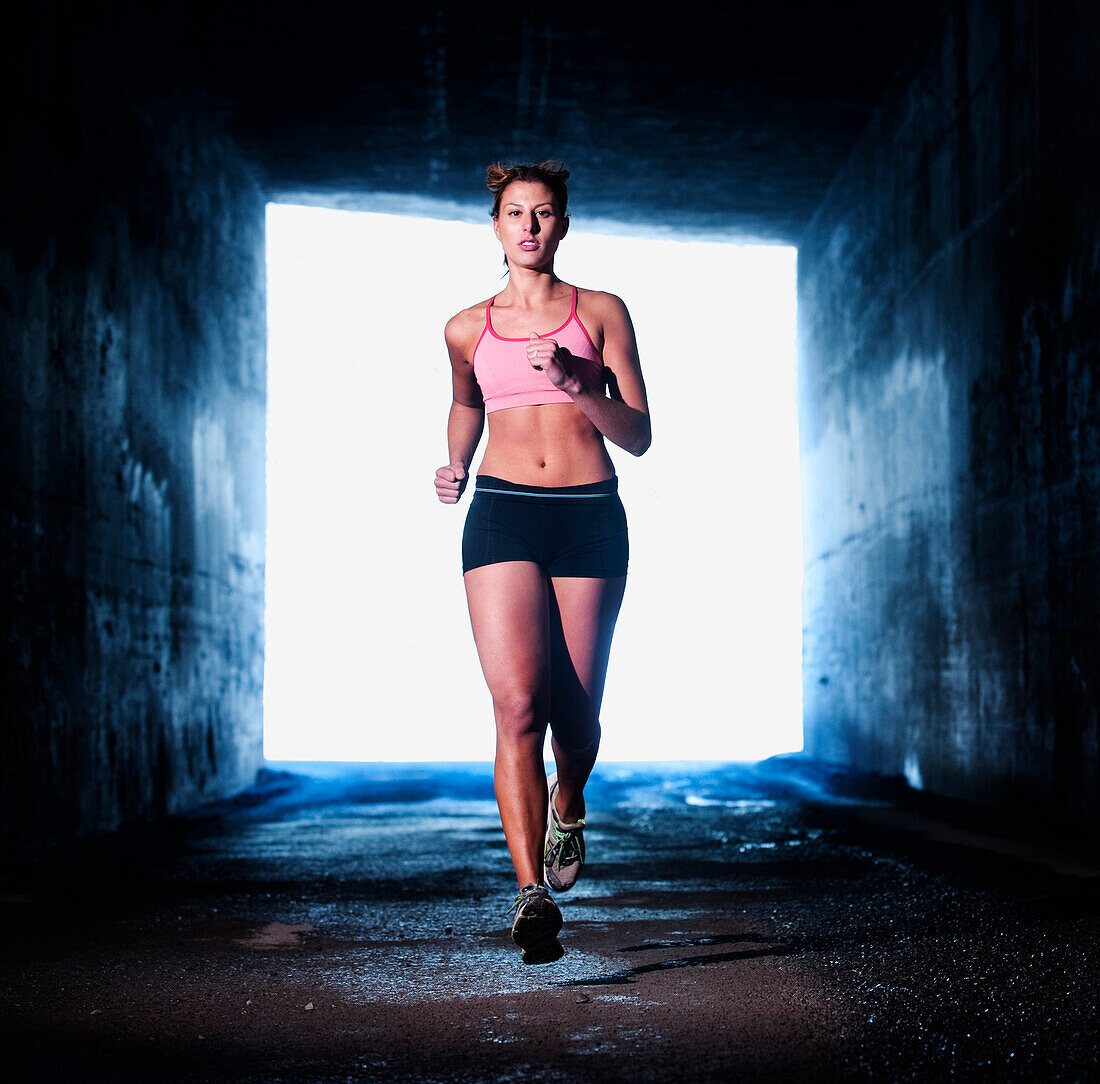 An athletic woman runs through a dark tunnel in Salt Lake City, UT Salt Lake City, Utah, USA