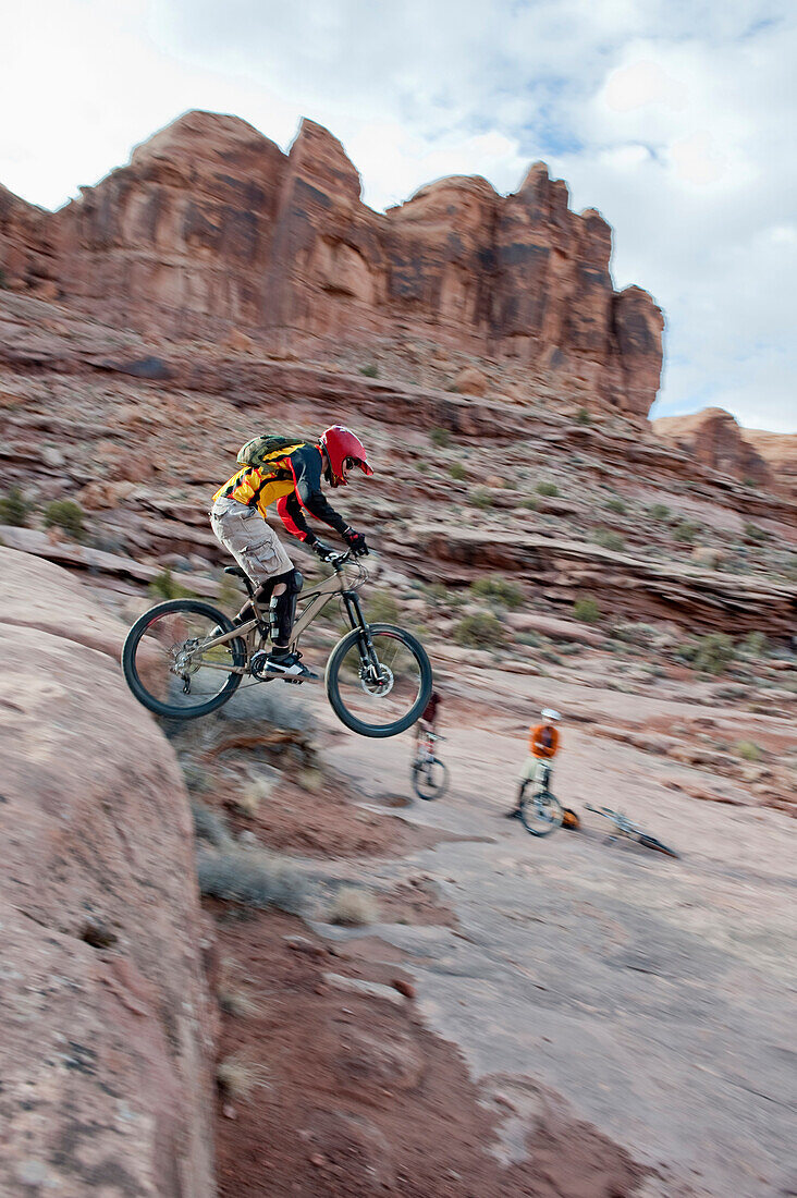 A downhill mountain biker launches off a drop on the Amasa Back Trail in Moab, UT Moab, Utah, USA