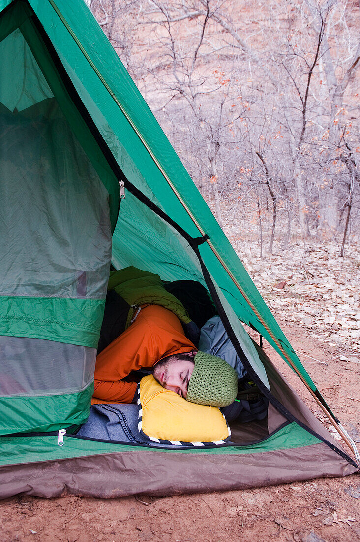A young man sleeps in an open tent, Moab, UT Moab, Utah, USA