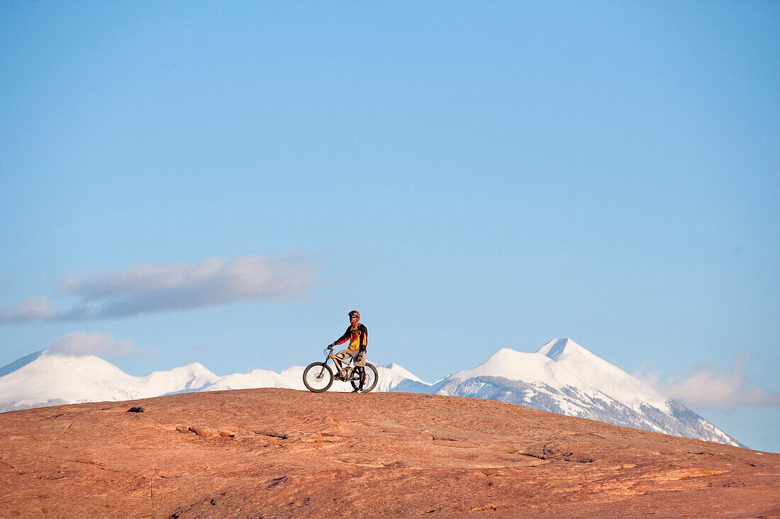 A mountain biker rests during a ride on the Slickrock Trail, Moab, UT Moab, Utah, USA