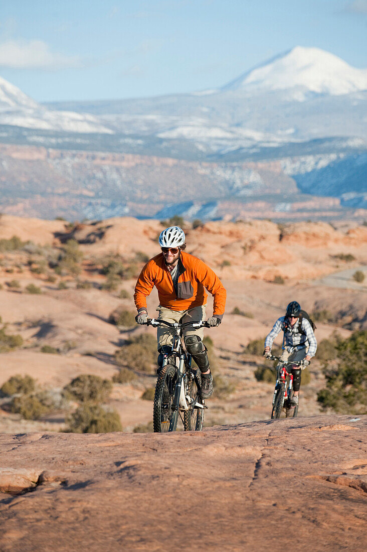 Two young men ride their mountain bikes on the Slickrock Trail, Moab, UT Moab, Utah, USA