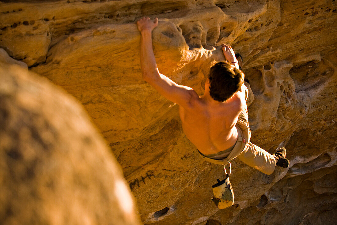 A young man rock climbs a boulder problem in Santa Barbara, CA Santa Barbara, California, USA