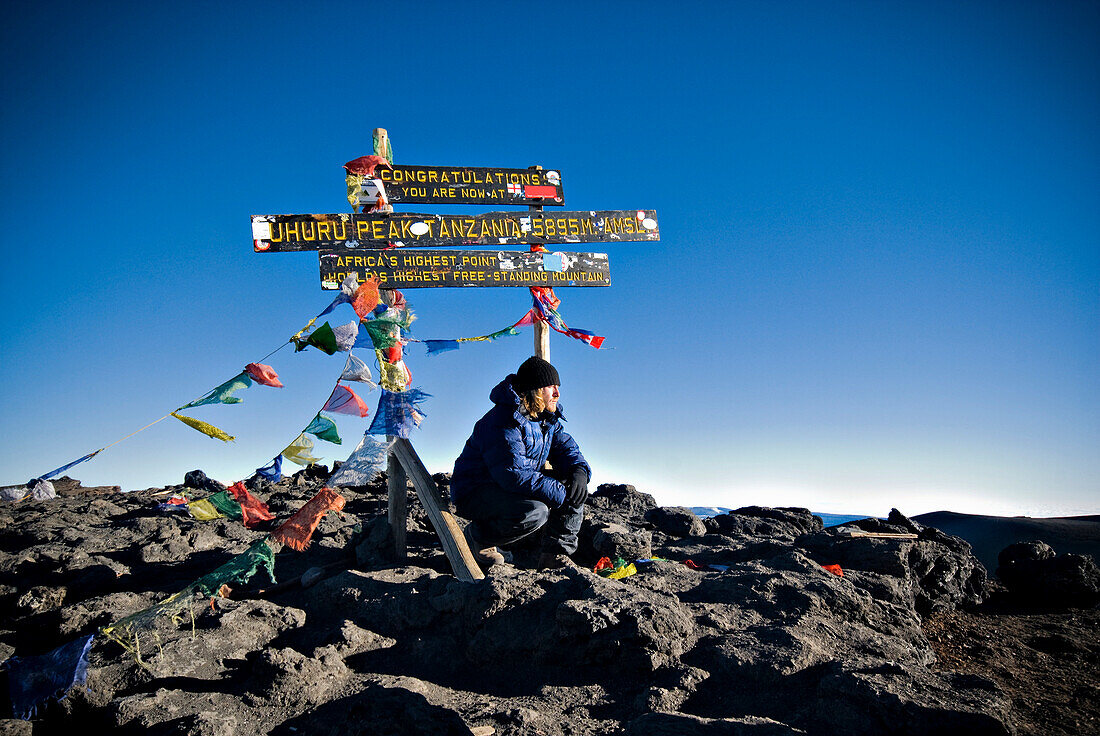 A young man reflects on the summit of Mt. Kilimanjaro, Tanzania, Africa as the sun rises Tanzania