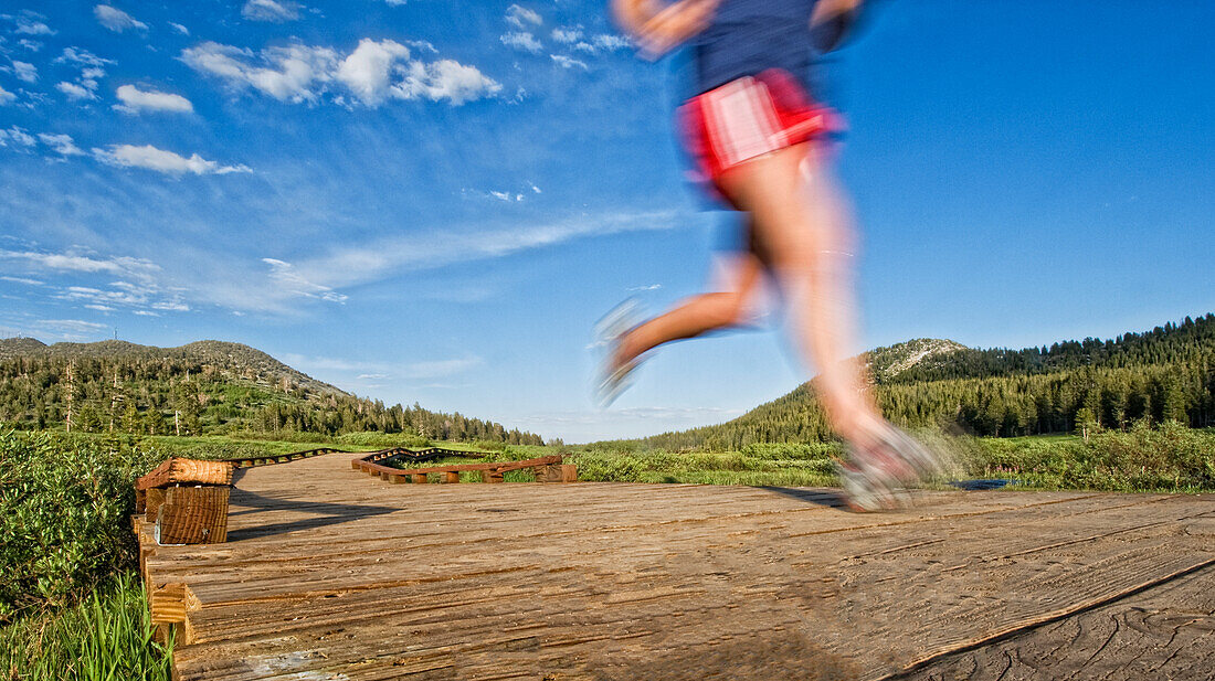 Heading in from an evening trail run, a young woman follows the wooden path back to the start in Lake Tahoe, Nevada Incline Village, Nevada, USA