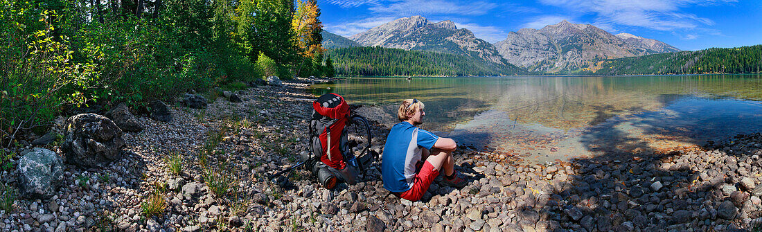 Hiker sitting by shady pebbly shore of Phelps Lake, Grand Teton National Park, WY, Jackson, WY, USA