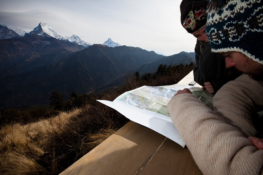 A trekking couple study a map from a viewpoint of Annapurna South in Nepal Annapurna Conservation Area, Nepal