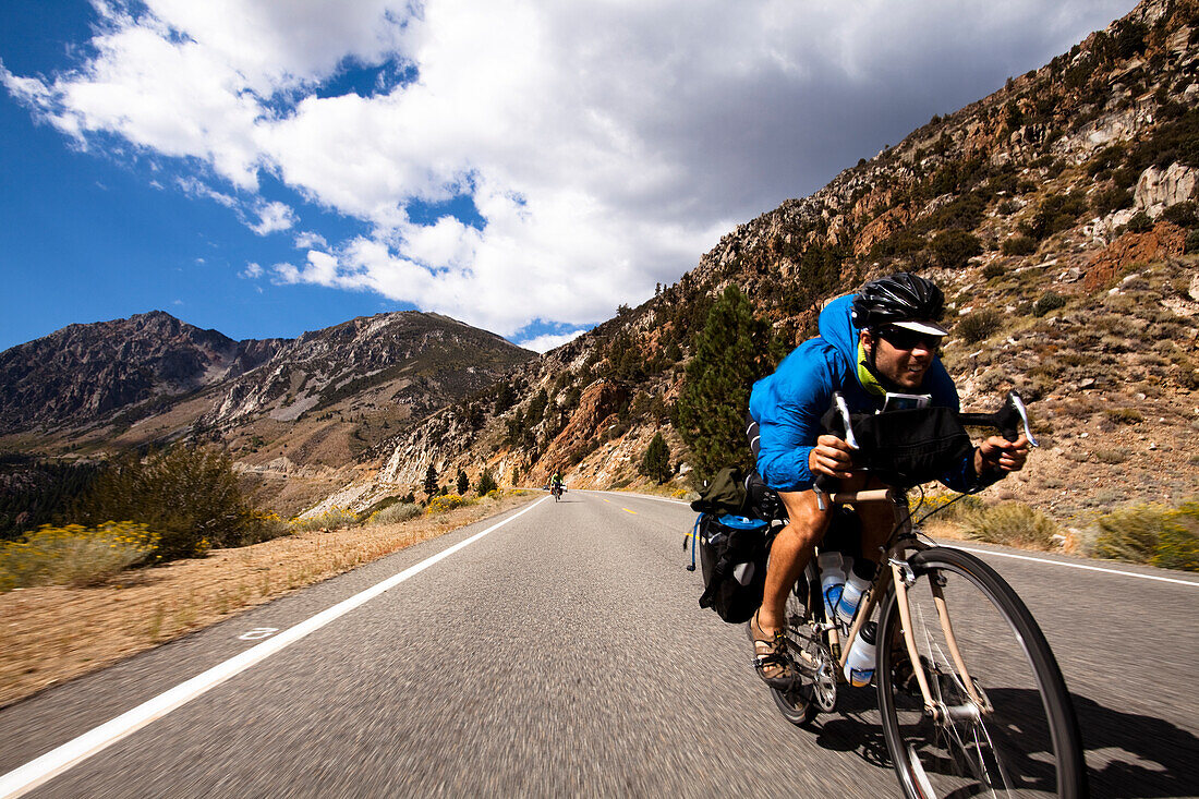 A male cyclist rides a loaded touring bike down the Tioga Pass in Yosemite, California Yosemite, California, United States of America