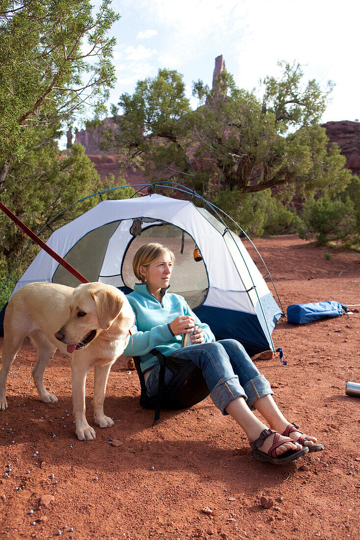 A woman and her dog enjoy a morning of camping outside of Moab, Utah Utah, USA
