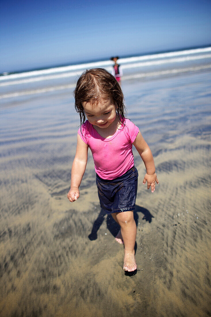 Young girl wearing a pink palying at the beach San Diego, CA, USA