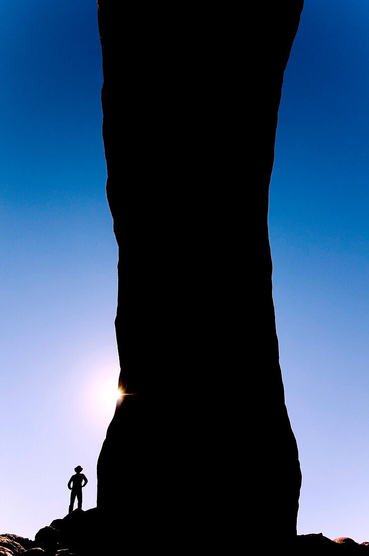 A silhouette of a man standing under North Window Arch in Arches National Park, Utah Arches National Park, Utah, USA