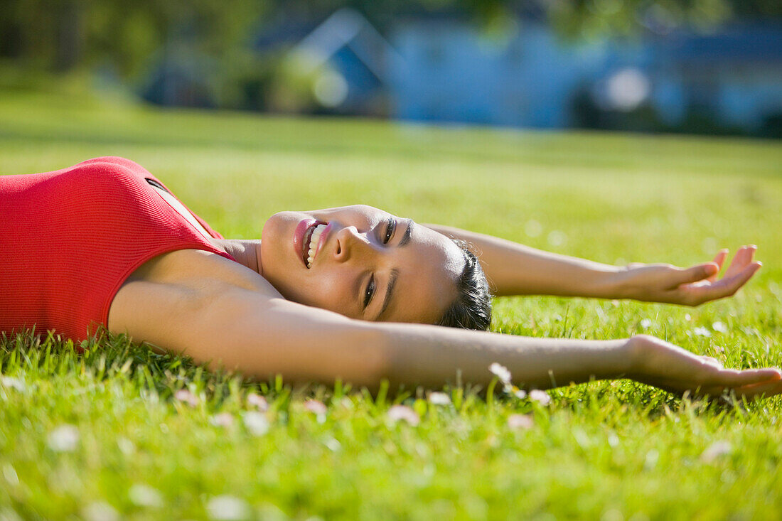 Hispanic woman laying in grass stretching, Seattle, WA