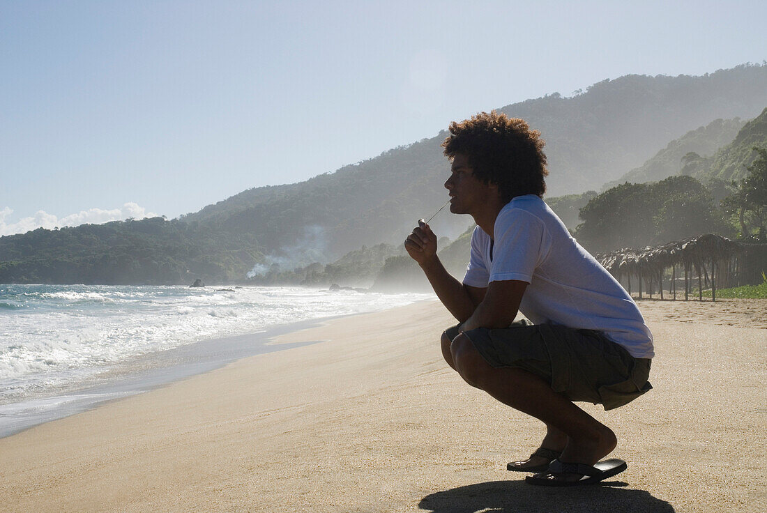 African man crouching at beach, Caruao, Venezuela