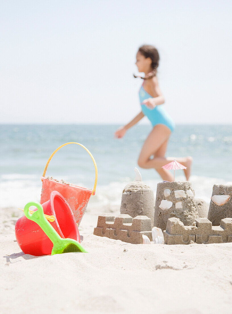 Hispanic girl and sand castle on beach, Rockaway Beach, NY