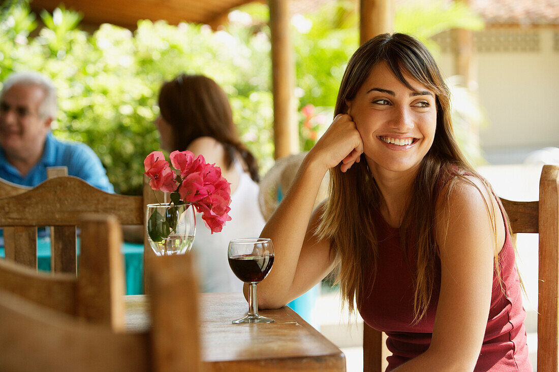 Smiling woman drinking red wine in cafe, Chorroni, Venezuela