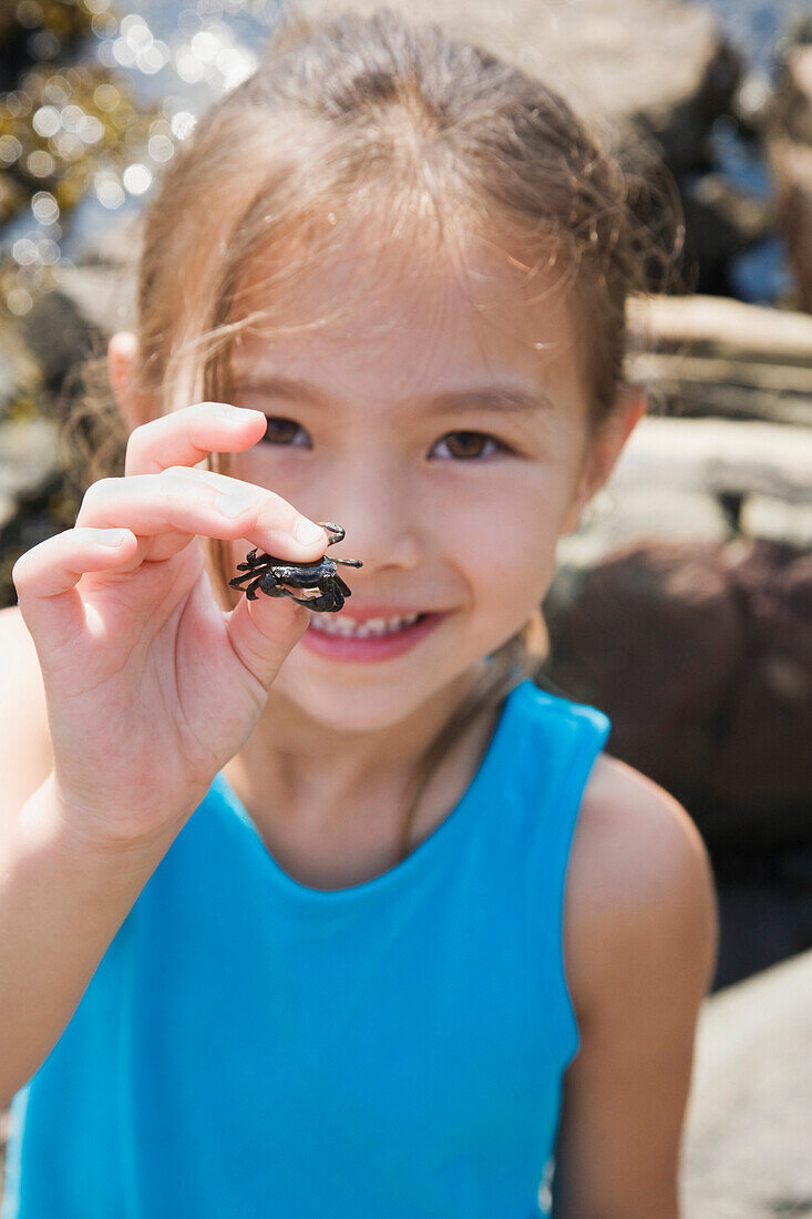 Asian girl holding tiny crab, Bellingham, WA