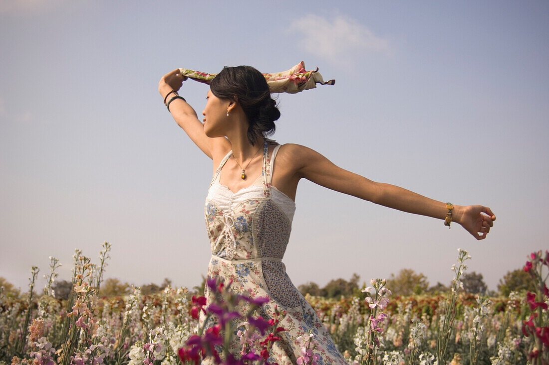 Asian woman with arms outstretched in meadow, California