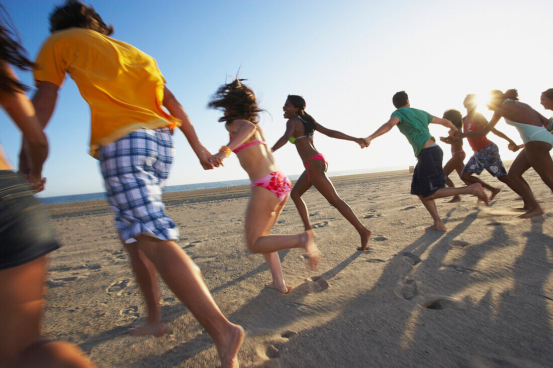 Multi-ethnic group of friends running on beach, Santa Monica, CA