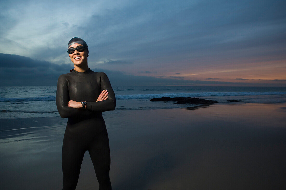 Hispanic woman in wetsuit on beach, Newport Beach, CA