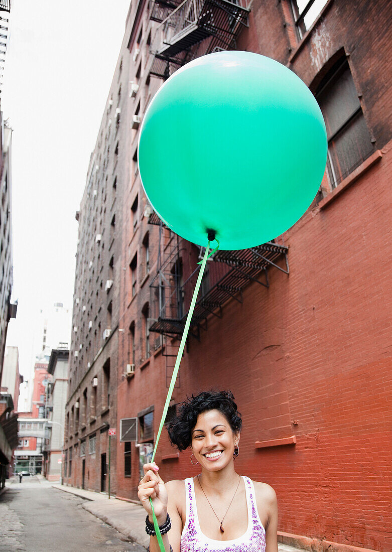 Mixed race woman holding balloon on urban street