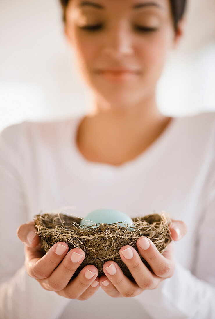 Mixed race woman holding nest with egg, Jersey City, New Jersey, USA
