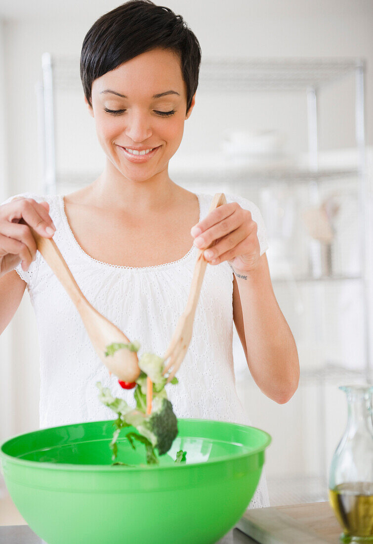 Mixed race woman mixing salad in kitchen, Jersey City, New Jersey, USA