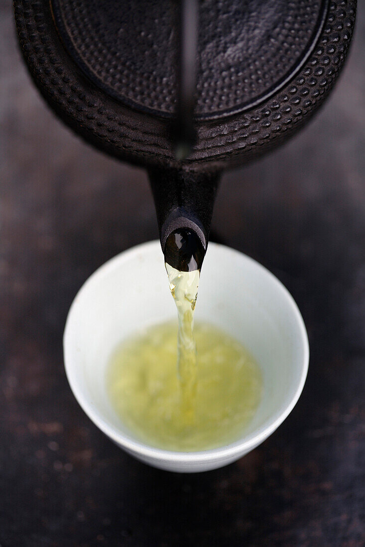 Close up of Japanese green tea being poured from teapot into cup, Santa Fe, New Mexico, United States