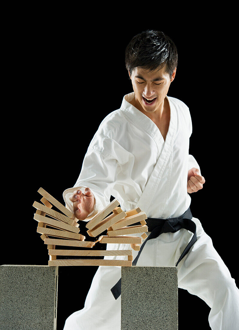 Asian male karate black belt breaking wooden planks, Jersey City, NJ, USA