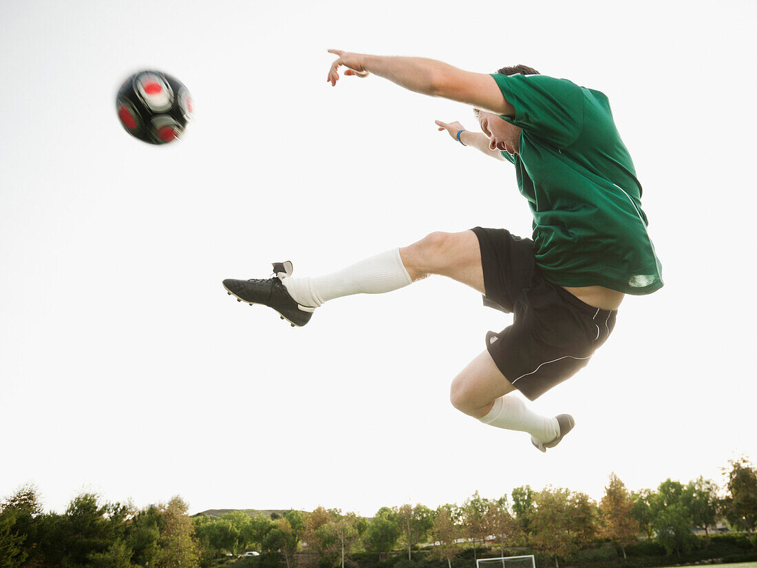 Caucasian soccer player in mid-air kicking soccer ball, Ladera Ranch, California, USA