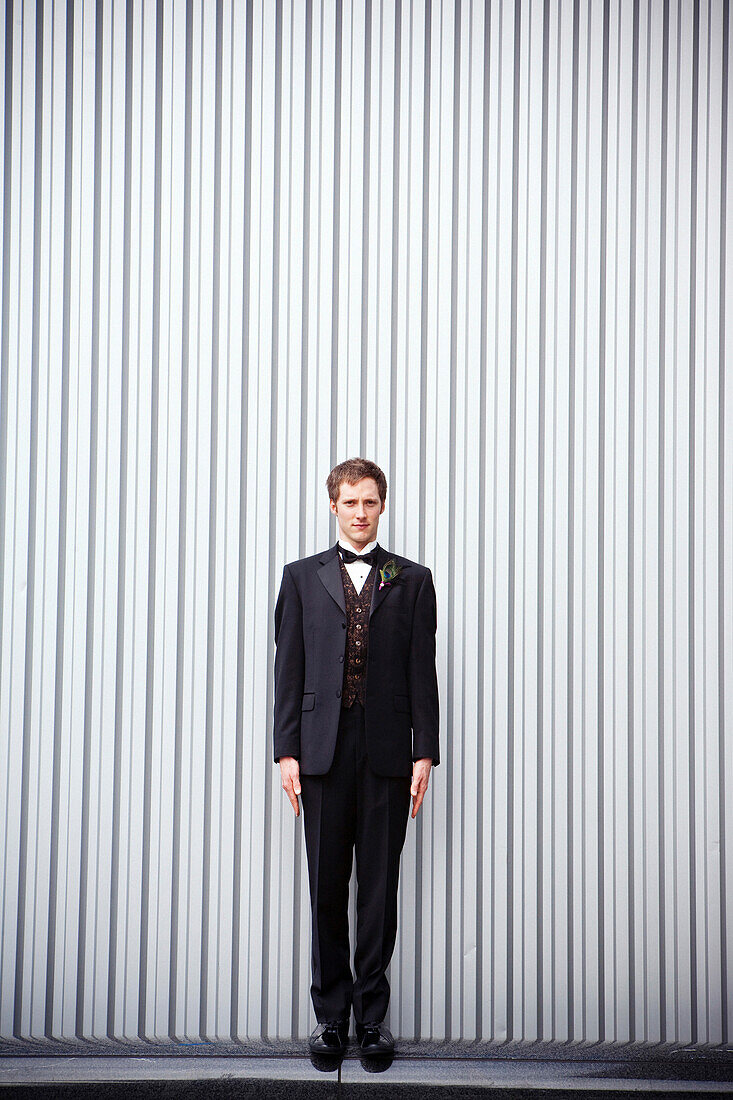 Serious groom standing near wall, San Francisco, California, USA