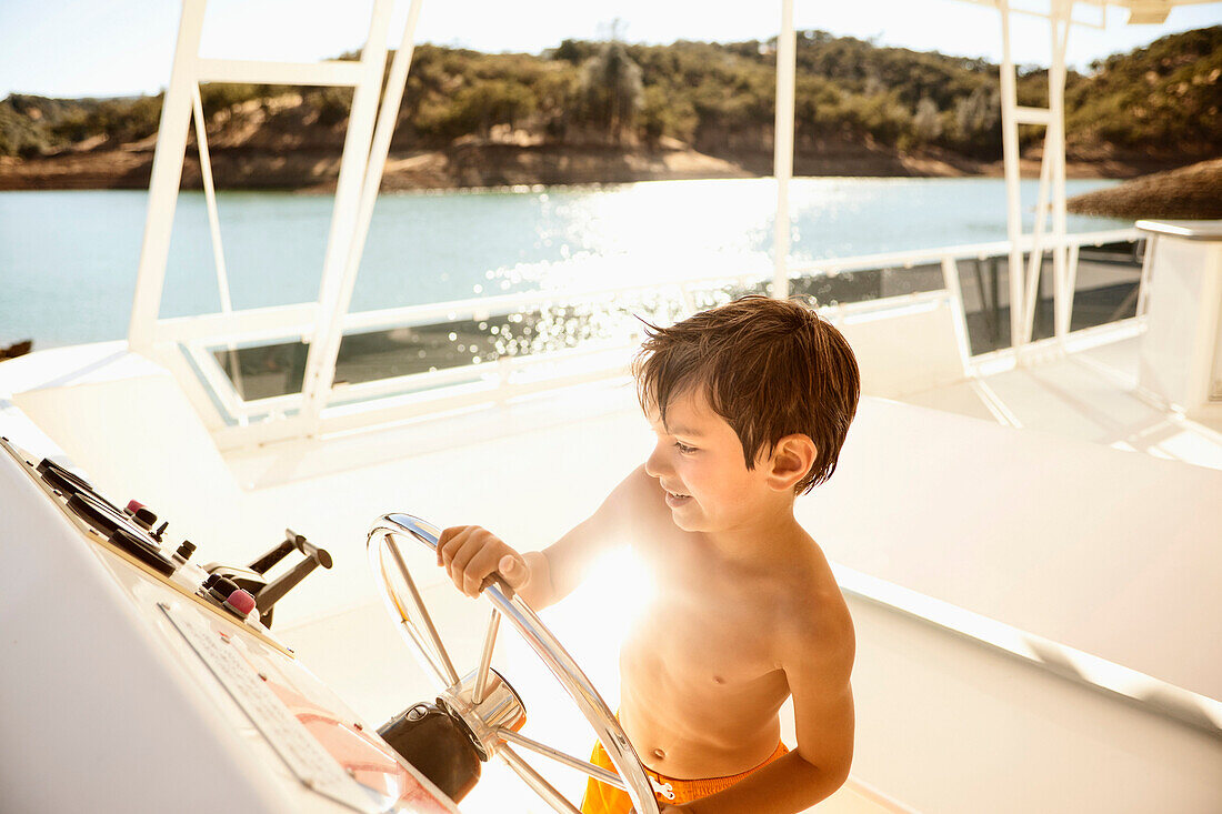 Mixed race boy steering boat on lake, Lake Berryessa, California, USA